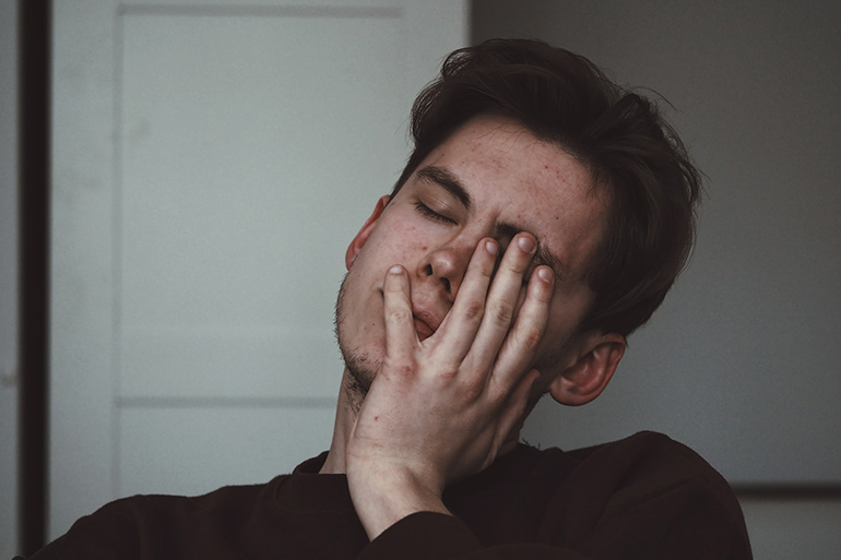 man sighing with closing his face by hand